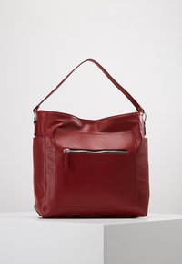 Sac à main en cuir synthétique rouge avec une seule bandoulière, doté d'une poche frontale zippée et d'un design lisse et sobre.