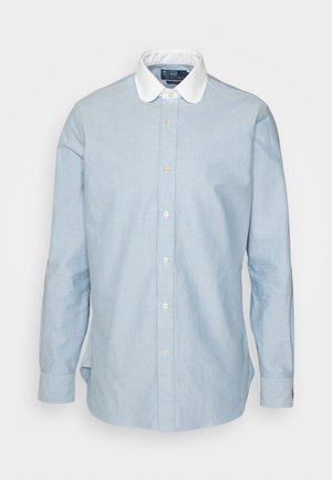 Chemise bleu clair à manches longues boutonnée avec col blanc contrastant et poignets boutonnés, présentée sur un fond uni.