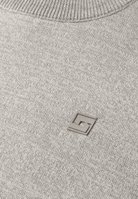 Tissu tricoté gris clair avec col côtelé et un petit emblème en spirale carré cousu près du centre.