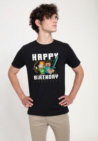 Black t-shirt featuring pixelated characters with tools, text reads "HAPPY BIRTHDAY," with green lines accentuating the design.
