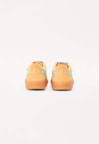 Zapatillas de ante naranjas con acentos azules, con un perfil bajo, punta redonda y suela de goma. Logotipo característico en el talón.