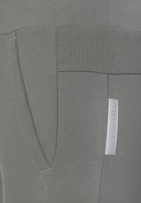 Graue Sweatpants mit einem gerippten Bund, Seitentaschen und subtilen Nähakzenten. Das Material scheint weich und leicht strukturiert zu sein.