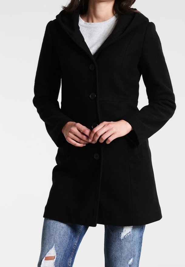 Abrigo de lana negro con capucha, con un cierre de botones en la parte delantera, dos bolsillos laterales y un diseño ajustado. Se lleva sobre una camiseta gris y jeans desgastados.