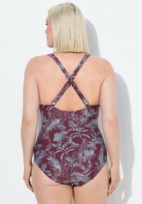 Maillot de bain une pièce bordeaux avec un design à dos croisé. Il présente des motifs de plantes tropicales et d'oiseaux en bleu clair. Fabriqué en matériau lisse et extensible.