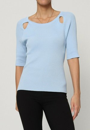 Haut en tricot ribbé bleu clair à manches courtes, avec deux découpes près de l'encolure, associé à un pantalon noir.