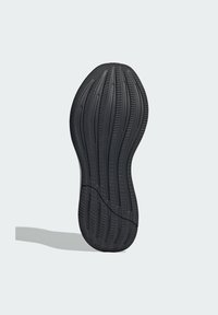 Semelle de chaussure en caoutchouc noir avec un motif ondulé et une surface texturée, présentant des rainures pour l'adhérence et une ligne centrale lisse.