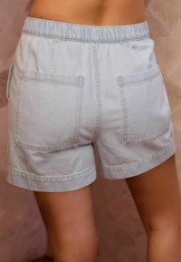 Gaiši zili denim šorti ar elastīgu jostu, divi aizmugurējie kabatas un salocītā mala. Audumam ir mīksta tekstūra un ikdienišķs piegriezums.