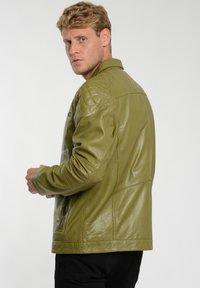 Olivgrüne Lederjacke mit gesteppter Schulterpartie, Reißverschlüssen und glatter Textur. Verfügt über einen klassischen Kragen und eine taillierte Passform.