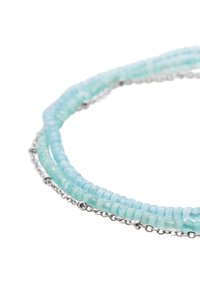 Warstwowa bransoletka z jasnoniebieskimi i akwamarynami koralikami o gładkiej teksturze, z dodatkiem srebrnego łańcuszka między warstwami koralików.