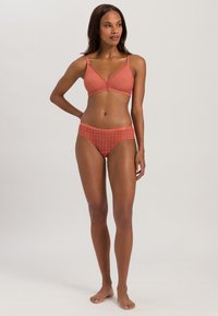 Koraalkleurige bh en bikini set met een geometrisch patroon, featuring dunne bandjes en een hooghals broekje. Zachte textuur en naadloos ontwerp.
