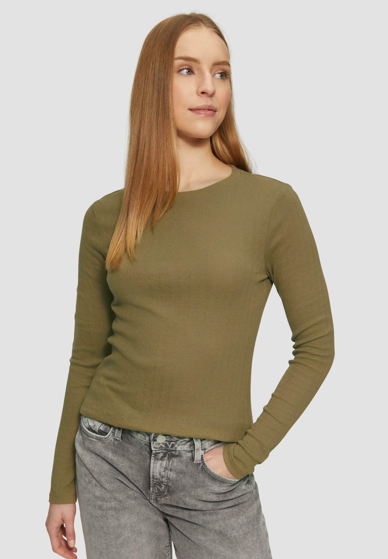 Olijfgroene shirt met lange mouwen, voorzien van een ribbelstructuur en ronde hals, gecombineerd met grijze jeans met een aansluitend ontwerp.