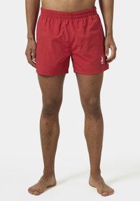 Pantaloni da bagno rossi con elastico in vita, realizzati in materiale leggero, con un logo sul lato anteriore sinistro. Texture liscia, lunghezza sopra il ginocchio.