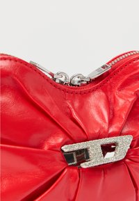 Κόκκινο δερμάτινο πουγκί με σχεδιασμό με πτυχώσεις, ασημένιο φερμουάρ και μεταλλικό κούμπωμα με κρύσταλλο στο κέντρο. Λεία υφή συνολικά.