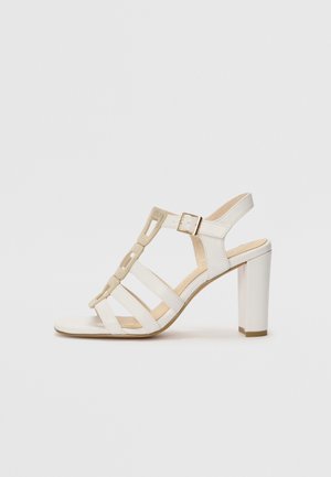 Sandal con tacco alto bianco e punta rotonda, dotata di cinturini beige, fibbia alla caviglia e tacco testurizzato. Finitura in materiale liscia.