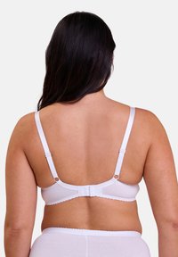 Soutien-gorge blanc avec bretelles réglables et fermeture à crochets. Présente des bords festonnés et une texture lisse pour plus de confort.