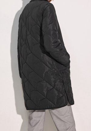 Cappotto lungo nero trapuntato con motivo a rombi, dotato di colletto e bottoni a pressione, realizzato in tessuto liscio e leggero.