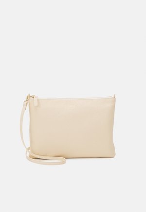 Pochette bracelet en cuir beige avec une fermeture éclair dorée et une bandoulière amovible sur un fond uni gris clair.