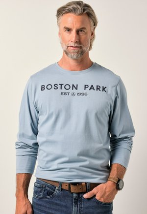 Light blue long-sleeve t-shirt featuring "BOSTON PARK EST 1996" in dark lettering. Soft cotton material, round neckline, and fitted sleeves.