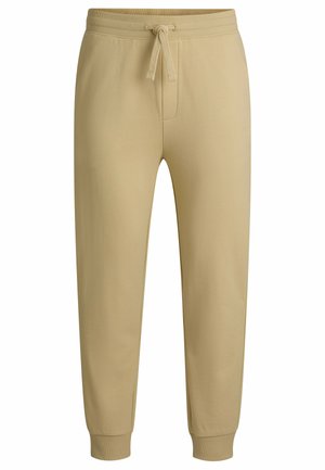 Pantalons de survêtement beige avec une taille élastique à cordon, jambes fuselées et poignets côtelés. Fabriqués en tissu doux en mélange de coton. Sans motifs visibles.