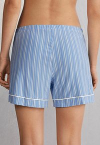 Blauwe en witte gestreepte shorts van lichtgewicht stof, met een elastische tailleband en witte piping aan de zoom.