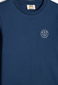 Marineblauwe katoenen sweatshirt met een ronde halslijn, voorzien van een klein wit geborduurd logo op de linkerborst. Soepele textuur, casual pasvorm.