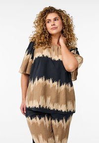 Lös passform på topp i svart och beige med ett vågmönster. Kort ärm, rund halsringning och textil med struktur. Matchas med koordinerade underdelar.