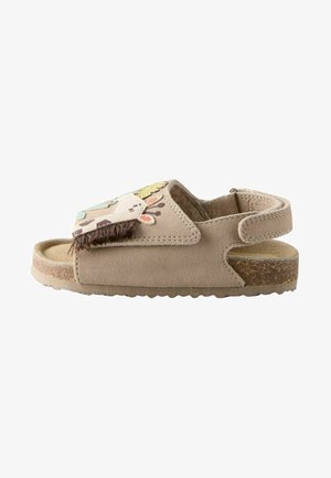 Sandalo beige per bambini con decorazione a forma di faccia di giraffa sulla cinghia e suola di sughero marrone.