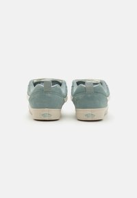 Blue suede sneakers with a low profile, white rubber soles, and a textured back tab. Features a logo on the heel.