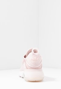 Rosa träningsskor med ett texturerat tygövre, rundad häl och en genomskinlig gummisula. Har en ögla bak för enkel påtagning.