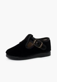 Scarpa in velluto nero con punta arrotondata, suola flessibile e cinturino decorativo con fibbia in materiale contrastante lungo i bordi.