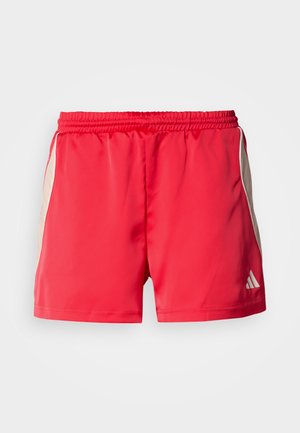 Punased sportlikud lühikesed püksid elastse vöökohaga, mille külgedel on kreemjad paneelid ja alumises paremas nurgas väike valge logo.