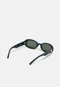 Black oval sunglasses with green lenses. Slim arms with a slight curve, featuring a gold accent on the side. Smooth, glossy finish.
