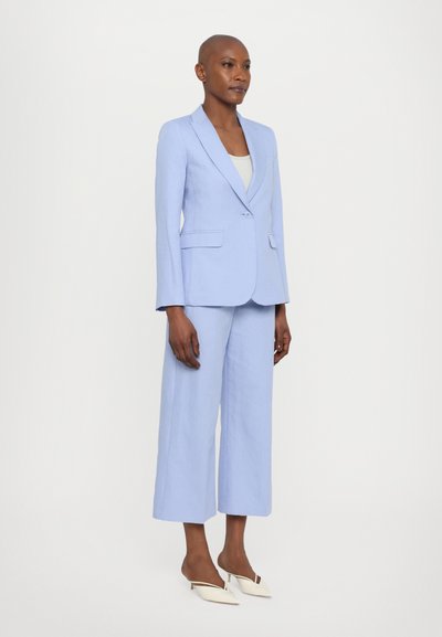 Svetlo modra tailored blazer s klasičnimi reverji, v kombinaciji s širokimi hlačami. Gladka tekstura, zapiranje z enim gumbom in minimalističen dizajn.