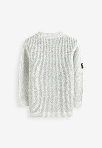 Ljusgrå stickad tröja med en texturerad ribbmönster, rundad halsringning och långa ärmar. Svart etikettinformation på vänster ärm.