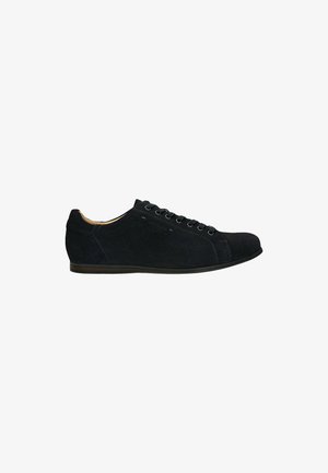 Sneaker in suede nero con punta arrotondata, lacci piatti e suola in gomma a profilo basso. Le cuciture decorative aggiungono una sottile texture e stile.