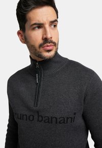 Dunkelgrauer Reißverschluss-Pullover aus geripptem Stoff. Hat einen hohen Kragen und das Logo "bruno banani" in dunklerem Grau auf der Brust.