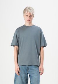 Grå bomulls-T-skjorte med avslappet passform, kortermet, rund hals og myk tekstur, kombinert med lyse denimjeans.
