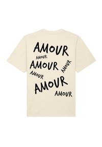T-shirt en coton beige avec du texte noir éparpillé qui dit "AMOUR" dans des tailles et orientations variées au dos.