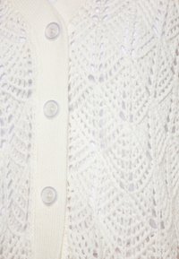 Cardigan bianco leggero con un motivo a maglia testurizzata e a rete, cinque bottoni in plastica davanti e colletto e orlo a costine.