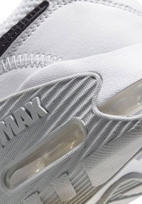 Witte sneaker met een gestructureerd leren en synthetisch materiaal, voorzien van een zichtbare luchtkusseneenheid en "MAX" branding in het grijs.