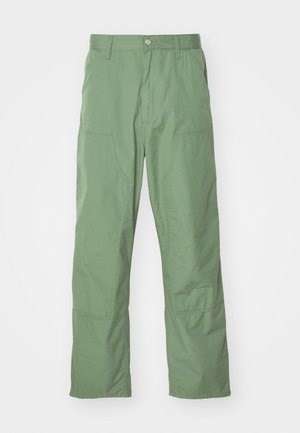 Svetlozelené nohavice vo voľnom strihu s hladkým povrchom, so bočnými vreckami a viditeľnými stehmi. Plnej dĺžky s rovný strihom nohavíc.