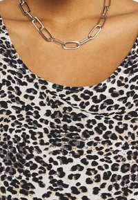 Leopardmönstrad topp med rundad halslinje, tillverkad av lättviktsmaterial. Har ett silverfärgat kedjehalsband med länkar.