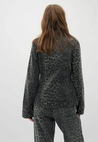 Leopardenmuster-Denimjacke in Dunkelgrün und Schwarz, mit einer taillierten Silhouette und langen Ärmeln, einer glatten Textur und kontrastierenden Nähten.