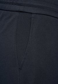 Černá tkanina s texturovaným povrchem; obsahuje boční kapsu a hladký pás. Texturovaný vzor zobrazuje diagonální čáry.