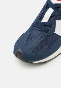 Mornarske atletske cipele od mrežastih i antilop materijala, s bijelim naglascima, crnim gumenim potplatom i površinskim detaljima s teksturom.