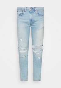 Ljusblå slitna jeans med revor vid knäna, femfickorsdesign och slim fit. Tillverkade av denim med en lätt blekt textur.