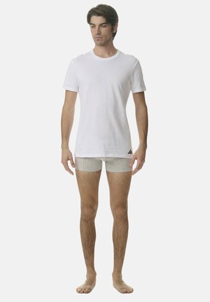 Weißes Baumwoll-T-Shirt kombiniert mit hellgrauen Boxershorts. Das Modell steht barfuß und präsentiert ein einfaches und funktionales Design ohne Muster.