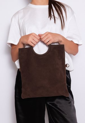 Borsa tote in suede marrone con un manico a taglio circolare, caratterizzata da una texture liscia e un design minimalista.