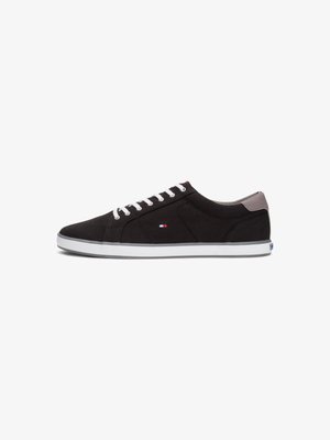 Black canvas sneakers with white laces, white rubber sole, and a gray back accent. Features branded logo on the side.