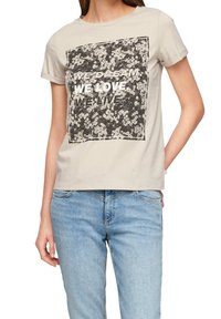 Světle šedé tričko vyrobené z bavlny, s černým květinovým vzorem a nápisem "SNÍME. MILUJEME. ŽIJEME." v tučných bílých písmenech.